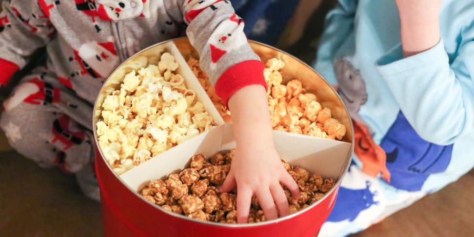 Kids in pajamas enjoy popcorn from a tin