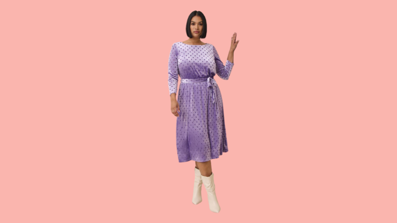 A model wearing a purple velvet midi dress with long sleeves and polka dots.
