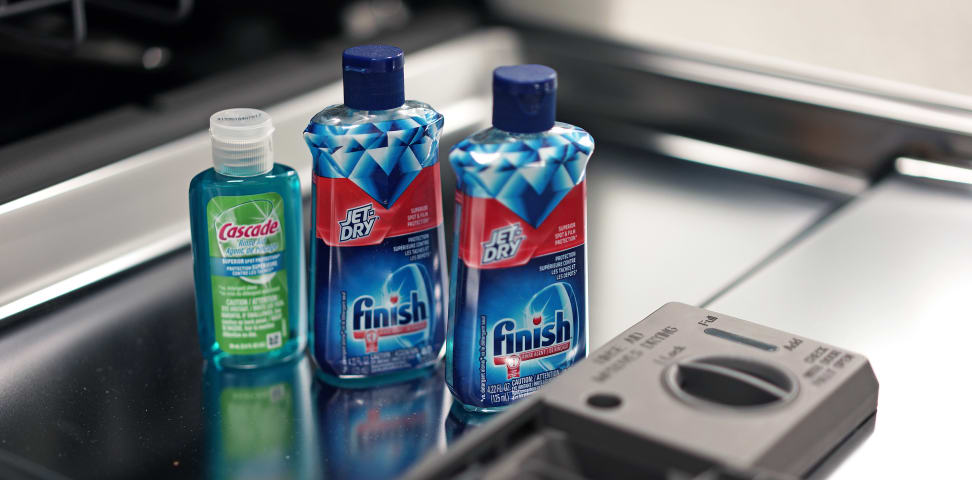 Bottles of rinse aid on an open dishwasher door.