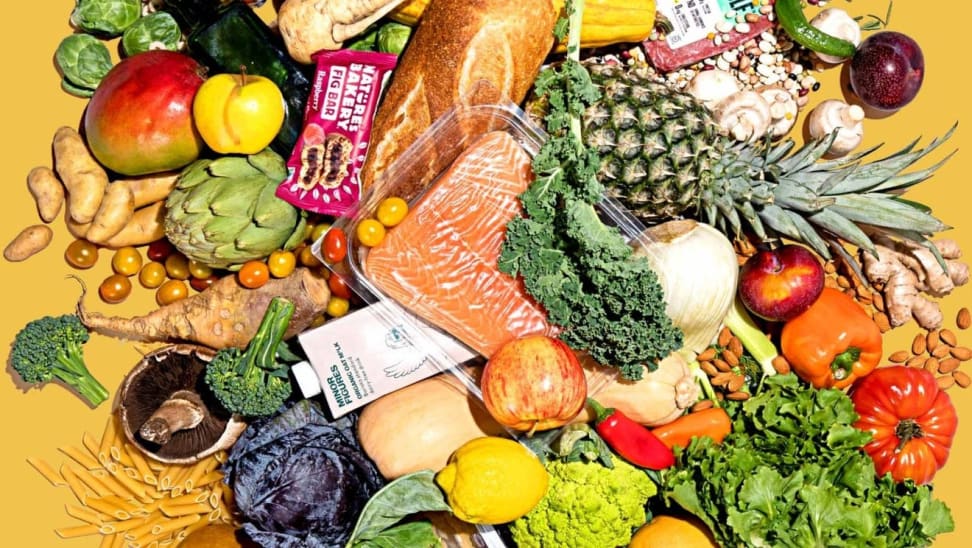 An assortment of fruit, grains, and vegetables sit on a yellow surface.