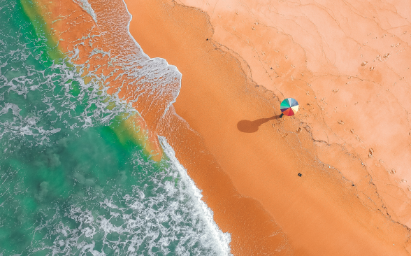 Aerial shot of a lone beach umbrella on a beach