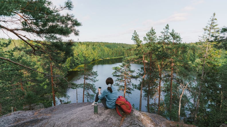 A woman sitting on a mountain looking out over a lake.