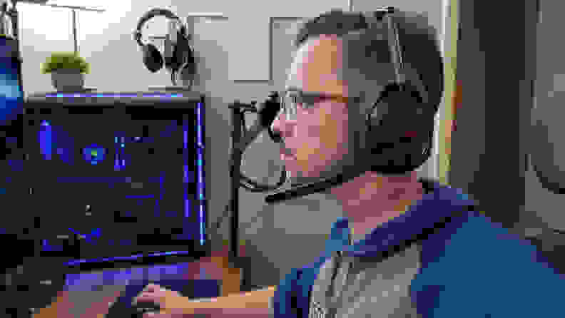 A man wearing a pair of Logitech Astro A50 X headphones while gaming on his PC.