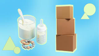 Powdered baby formula next to teething ring, baby bottle and three stacked shipping boxes.