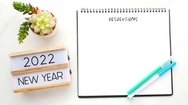 a potted succulent and a sign that reads 2022 New Year stand next to a blank notebook
