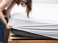 A person puts a mattress protector on a mattress