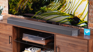 The Samsung HW-Q990C soundbar on a wooden home theater credenza in front of a TV.