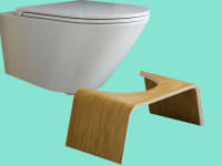 Wooden Squatty Potty in front of modern-looking toilet against teal background