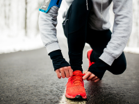 一个女孩在冬季跑步时弯腰系鞋带。