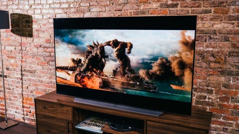 LG TV on television stand against brick wall.