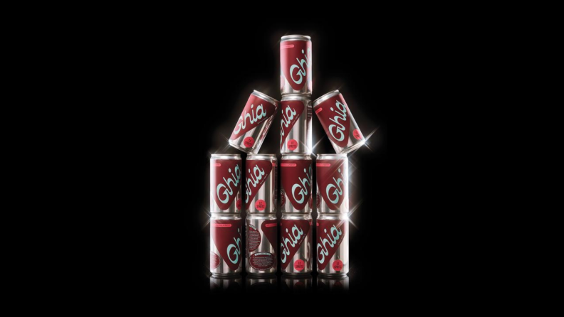 A stack of cans of Ghia non-alcoholic spritzes against a black background.