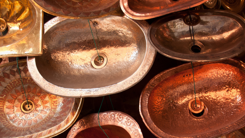 Handmade brass and copper sinks sit on display at a market.