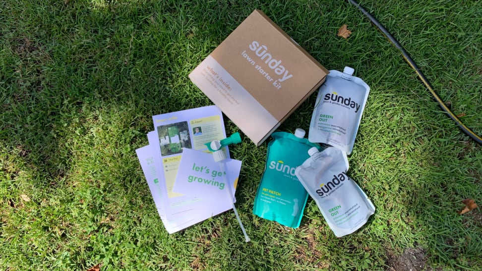 Sunday lawn care products sitting on green grass next to a garden hose.