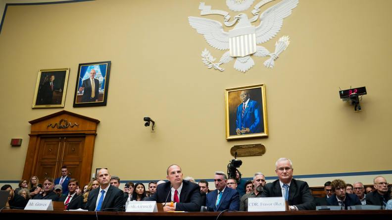 A photograph of a panel of government officials at the US Department of Defense.