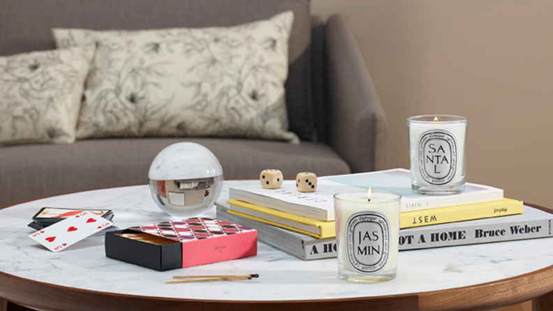 Two scented candles sit on a coffee table in a living room.