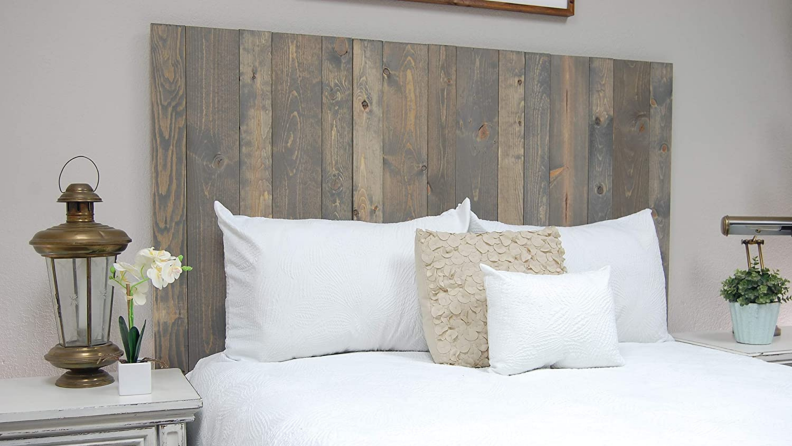 Barn wall headboard behind bed with pillows .