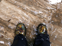 穿靴子的人站在被几英寸深的水覆盖的硬木上