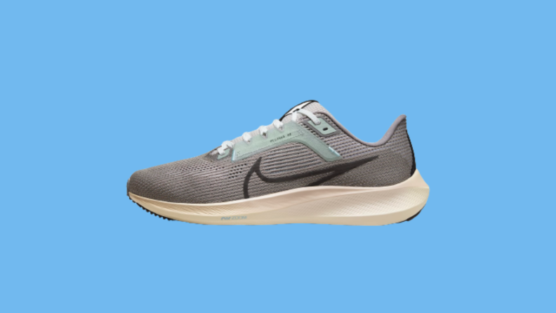 A gray and green sneaker against a blue background.