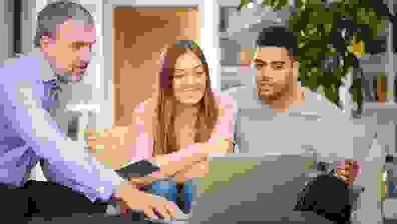A millennial biracial couple sits down with a loan officer in front of a computer