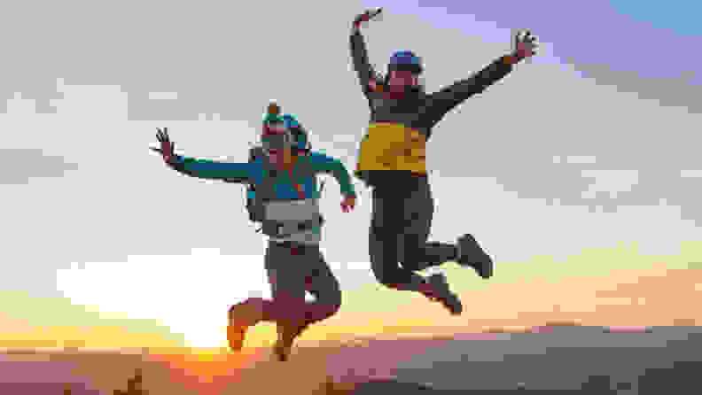 Two people jumping in L.L.Bean clothes on a mountain