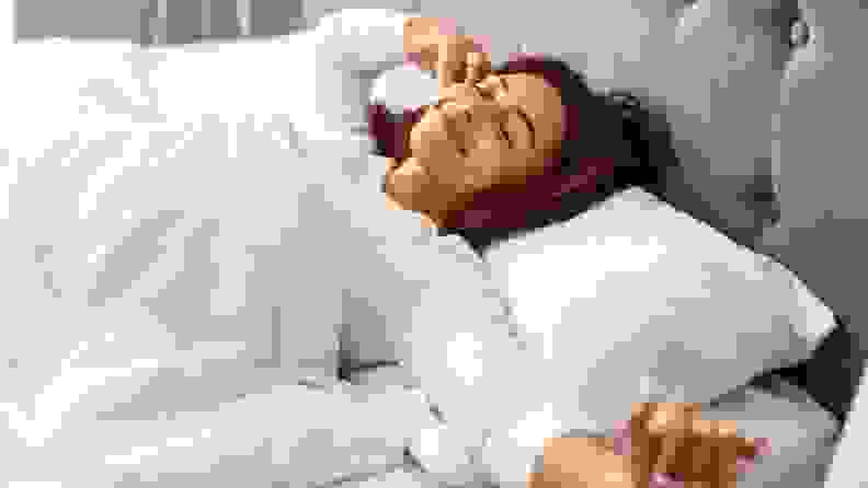 A person stretches in bed.