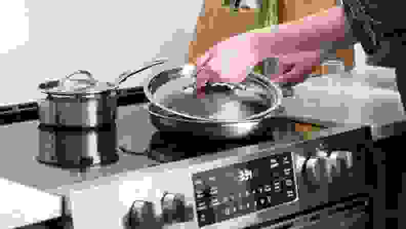 Woman covering pan with lid as she cooks