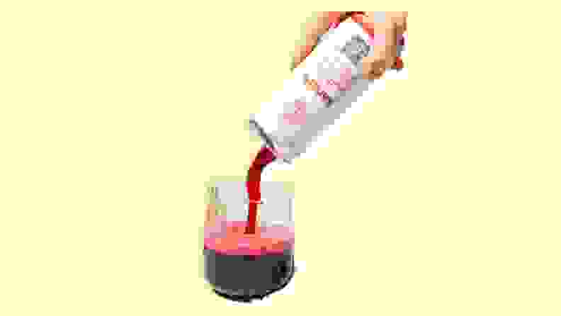 A can of sangria being poured into a wine glass on a yellow background