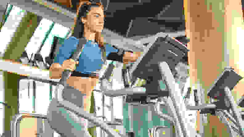 A woman using an elliptical machine at the gym.