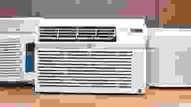 Three white window air conditioners are displayed on a wooden countertop.