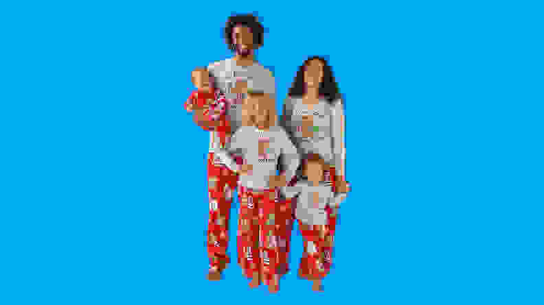 A family wearing Nite Nite Munki Munki Star Wars Chewy matching family holiday pajamas on a blue background.