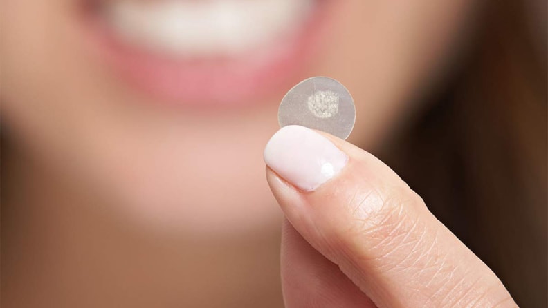 A woman holds a used acne patch.