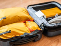 An open suitcase filled with yellow packing cubes.