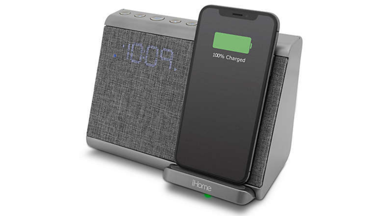 A grey alarm clock against a white background. Includes an iPhone charging station. iPhone is pictured.