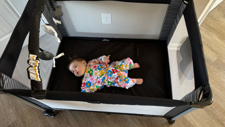 A child laying flat inside of the Graco Pack 'n Play On the Go Playard.