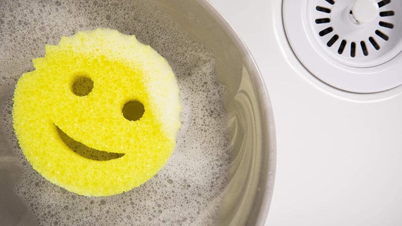 Smiley face sponges in pot in sink.