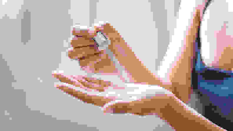 A closeup on a person's hand using a dropper to dispense liquid into their other hand.