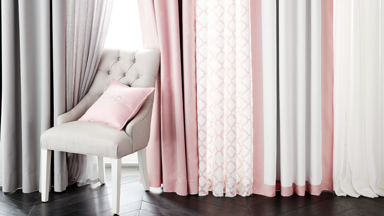 Tan chair in front of pink, gray, and pink patterned drapes