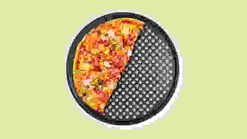 Half a pizza on a perforated tray on a beige background.