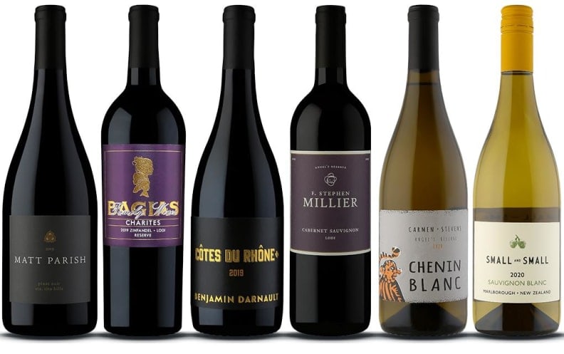 Six bottles of assorted red wines in a row.