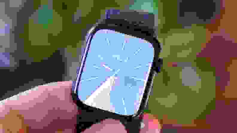 Person holding the Apple Watch Series 9 in their fingers outdoors.