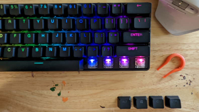 Four keys plucked off an illuminated Apex Pro Mini keyboard.