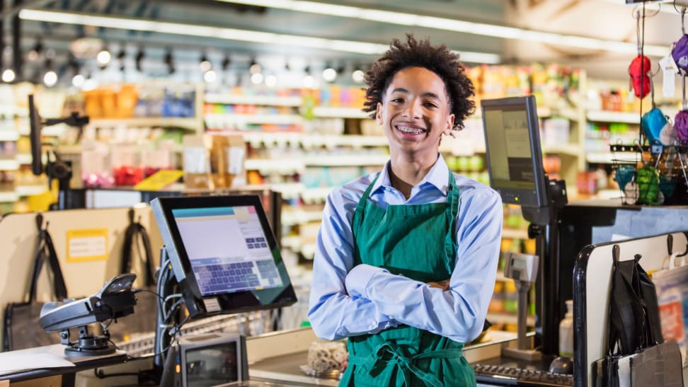 Teenager standing next to a register crossing his arms