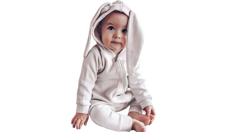 An adorable child in a bunny-eared romper