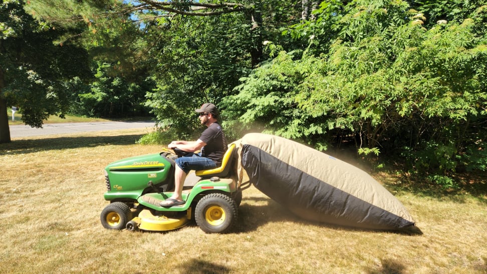 Person riding on lawn mower with the TerraKing 54 cubic foot Pro Leaf Bag on back.