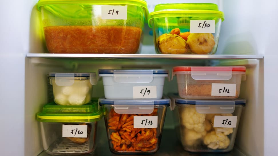 Several labeled containers of food stacked in a fridge