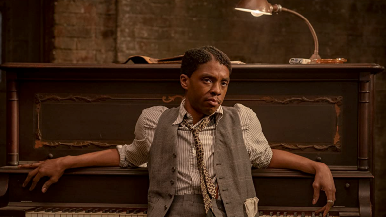 电影中的黑色黑色底部静止不动，演员查德威克·鲍斯曼（Chadwick Boseman）靠在钢琴上