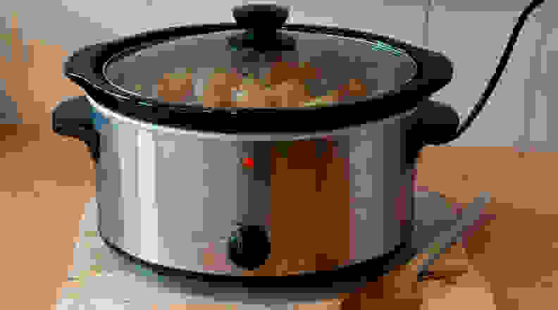 Slow cooker on counter with wooden spoon