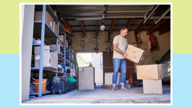 Person standing in garage while holding moving boxes indoors.