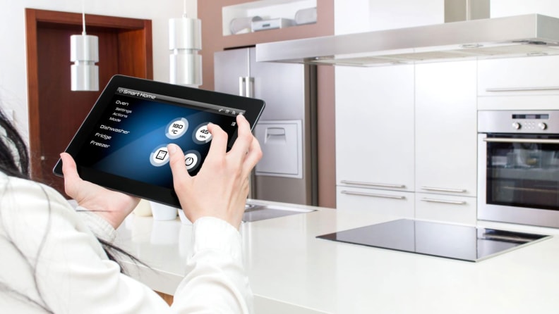 A person holding a tablet with a smart home app on display.