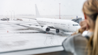 Plane on a snow-covered airport during with a woman looking out a window